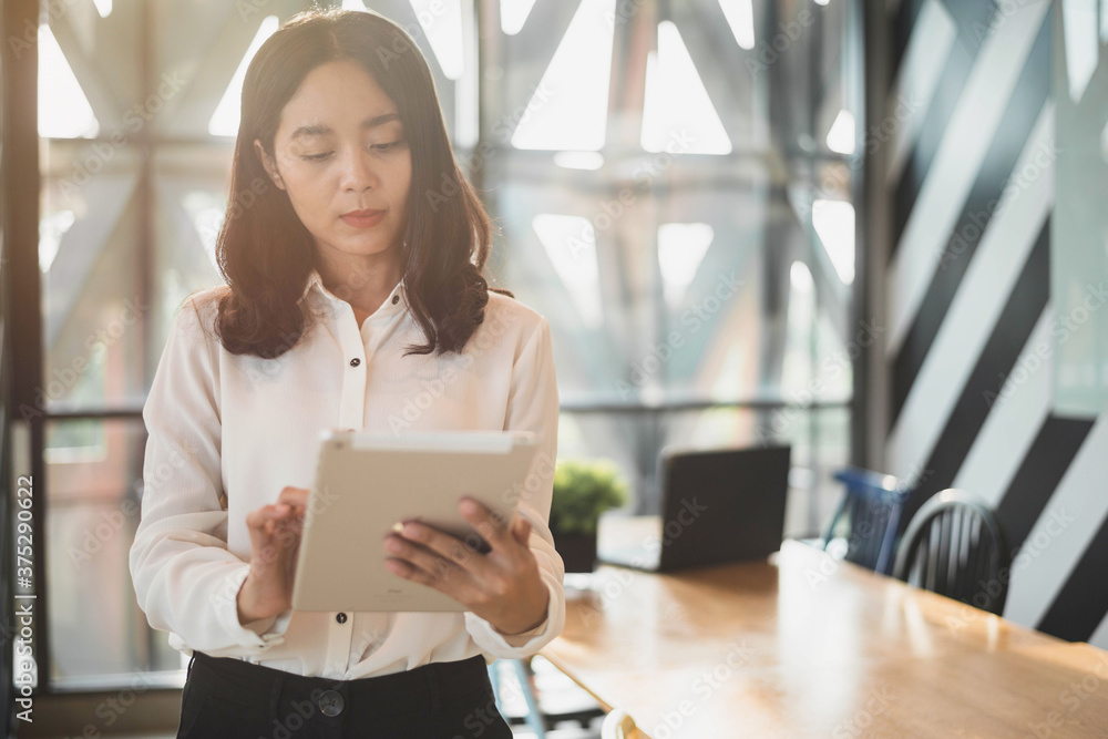 Business woman using a digital tablet in office. Asian woman working with tablet in office Business woman using a digital tablet in office. Asian woman working with tablet in office