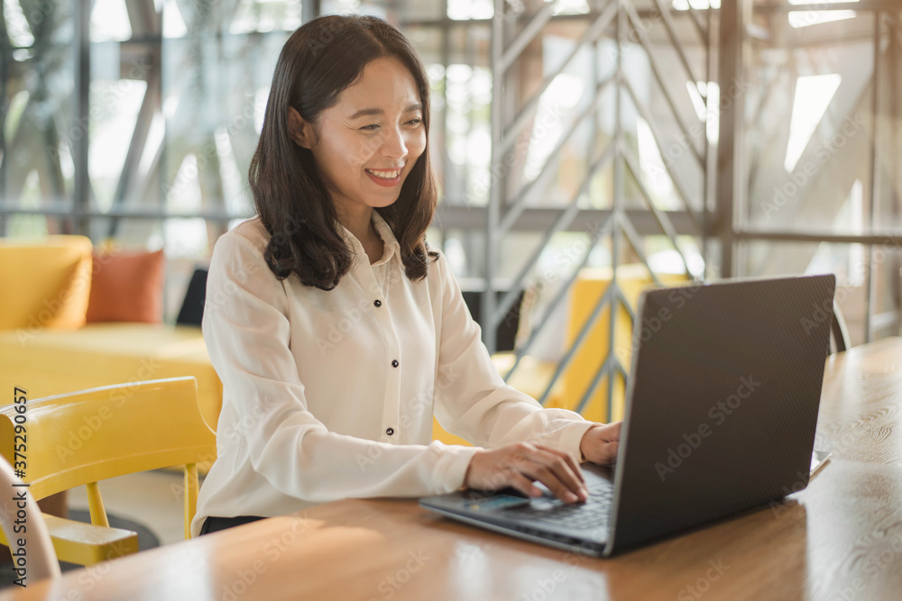 Smiling Asian businesswoman working on a laptop at her desk. Business woman working from home in quarantine. Smiling Asian businesswoman working on a laptop at her desk. Business woman working from home in quarantine.