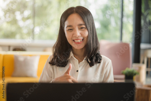 Happy asian woman sitting at desk and video conference calling on laptop at home.