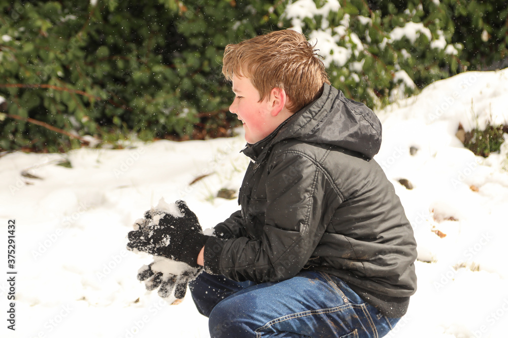 Young boy playing in the snow making snowballs. Winter happiness in Australia 2020