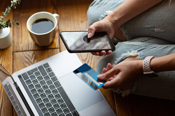 Young woman holding credit card and using laptop computer. Online shopping, e-commerce, internet banking, spending money, working from home concept