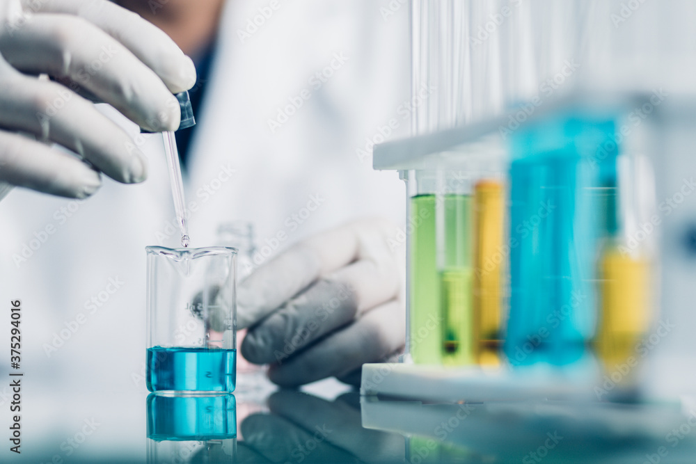 Hand of Biochemical research scientist working with science laboratory test tubes for coronavirus vaccine development in pharmaceutical research labolatory. Hand of Biochemical research scientist working with science laboratory test tubes for coronavirus vaccine development in pharmaceutical research labolatory.