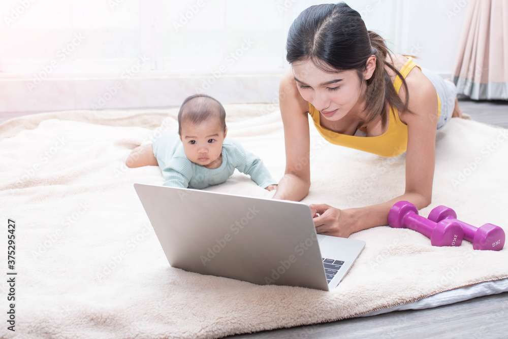 Asian mother fit and play Yoga for lose weight after delivery a new born baby in home, mother, exercise and healthy concept. mother watching videos on laptop, training in living room.. Asian mother fit and play Yoga for lose weight after delivery a new born baby in home, mother, exercise and healthy concept. mother watching videos on laptop, training in living room..