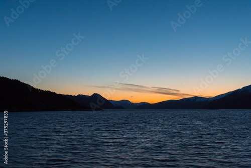 Dawn over the coastline of Norway with hills and mountains seen from cruise ship