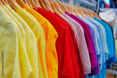 Bright colorful t-shirt collection on store rack in all colors of the rainbow 