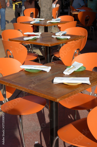 Orange chairs at a bright outdoor dining restaurant with white table setting