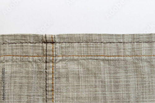 Linen fabric texture. Close-up. A fragment of linen cloth. Rough fabric texture. Double machine stitching on fabric. Decorative elements of trousers. Loose threads. A series of photographs. Flat lay