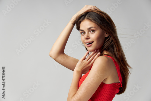 Side view of pretty brunette woman in red t-shirt touches her face with hand 