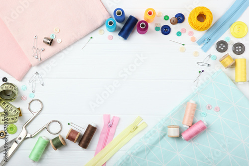 different sewing accessories on the table. Threads, needles, pins, fabric and sewing scissors close up 