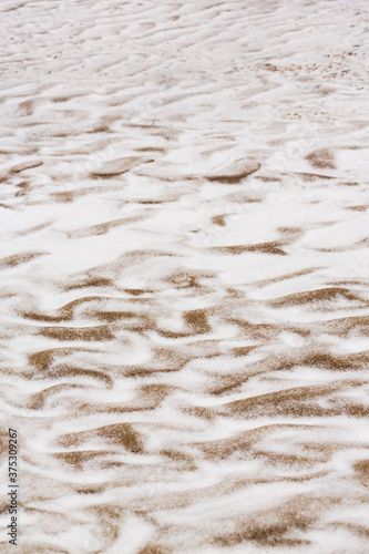 Abstract shapes with sand dunes covered by fresh powder snow, in a wild river bed, in winter