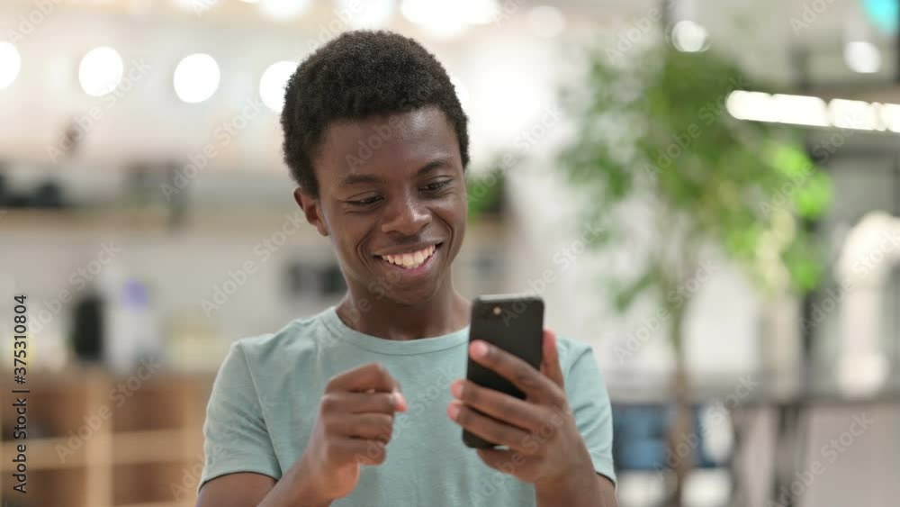 Young African Man Celebrating Success on Smartphone Young African Man Celebrating Success on Smartphone