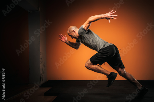 Billede på lærred Side view of male athlete sprinting inside a gym.