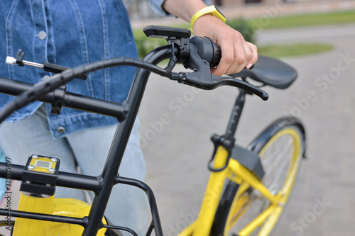 Bicyclist holds yellow Bicycle behind wheel. Bicycle rental and rental concept