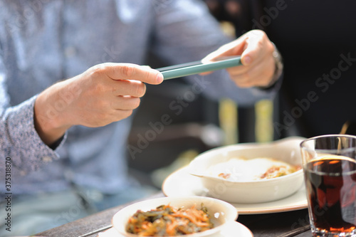 Cafe visitor photographs his lunch with smartphone. Food blogger review at bistro concept