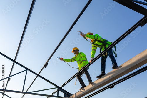 Asian worker wear safety height equipment to build a steel roof structure in the construction site.