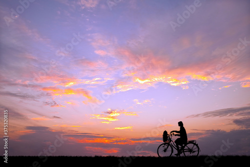 夕陽を背景に自転車通学する女子高校生のシルエット