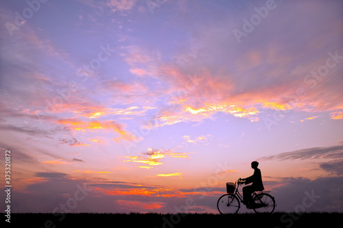 夕陽を背景に自転車通学する男子高校生のシルエット