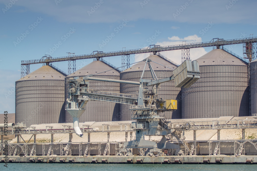 Obraz premium Shiploader at the berth of the sea grain terminal, mooring gallery, silos. General view of the grain terminal.