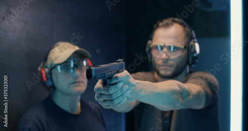 Mature instructor teaching man to shoot pistol photo