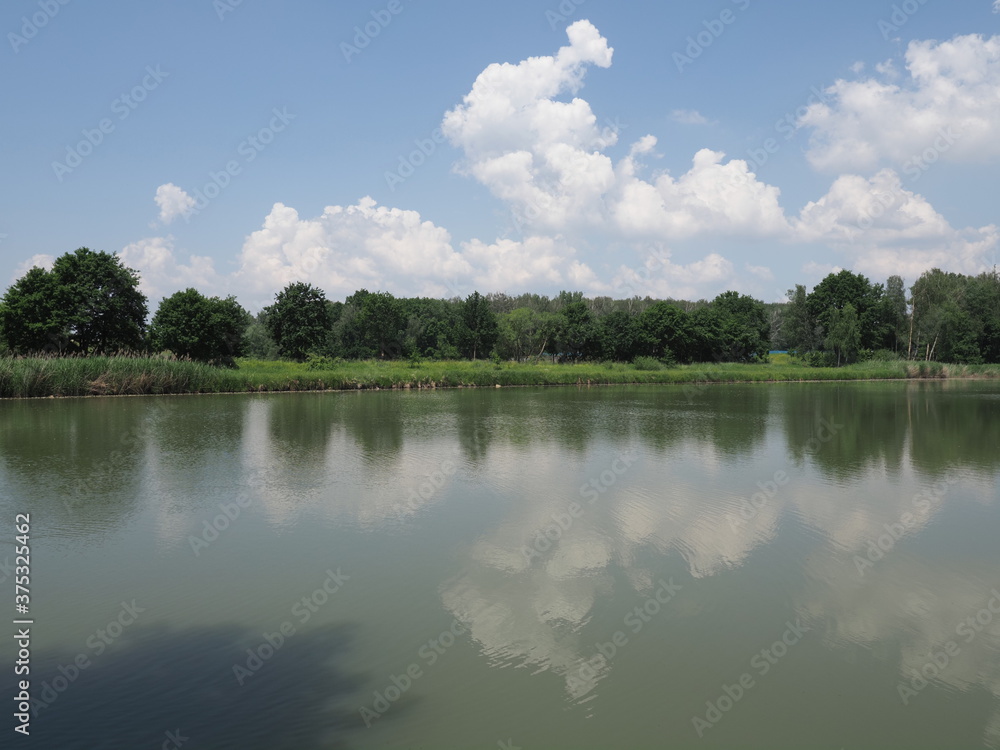 Landscapes reflected in waters of artificial lake in european Goczalkowice town at Silesian district in Poland, clear blue sky in 2020 warm sunny spring day on June. Landscapes reflected in waters of artificial lake in european Goczalkowice town at Silesian district in Poland, clear blue sky in 2020 warm sunny spring day on June.