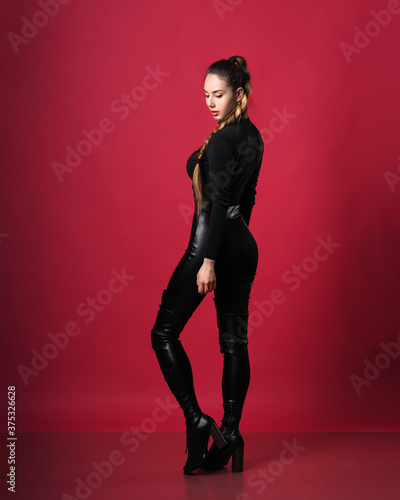 Brunette model at latex posing at the red background © Sergii Mironenko