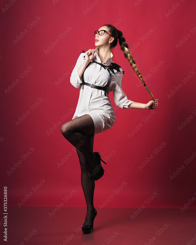 Brunette model at skirt posing at the red background Brunette model at skirt posing at the red background
