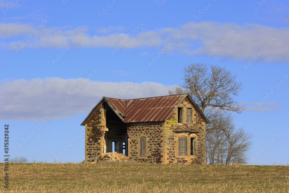 Old Limestone house in the country in a field with blue sky and white clouds. Old Limestone house in the country in a field with blue sky and white clouds.