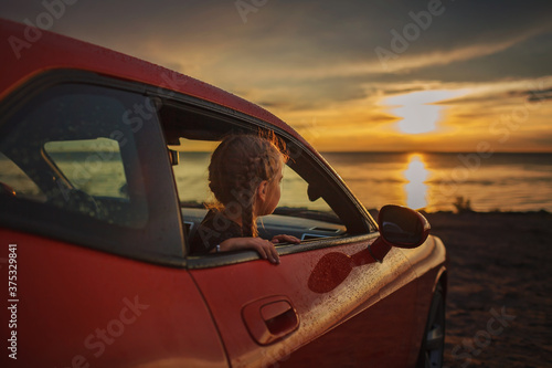 Freedom and family traveler. Woman sitting in the car on the bank of sea after rain © Maria