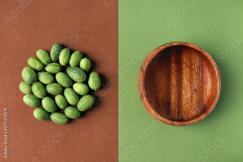 Cucamelon, round wooden plate on textured paper background. Nature, balance, geometry concept. Organic design, grassy green brown colors. Minimalistic horizontal poster. Eco tableware, plant, flat lay photo