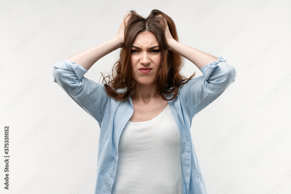 Obraz premium Photo of brunette female with long straight hair, holding hands on head. Problems, surprise, fear, fobia concept