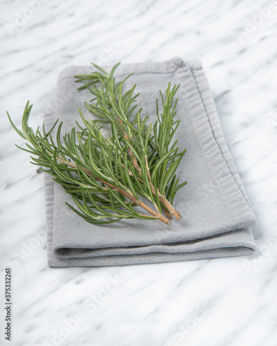 Rosemary sprigs from kitchen garden on tablecloth on marble background