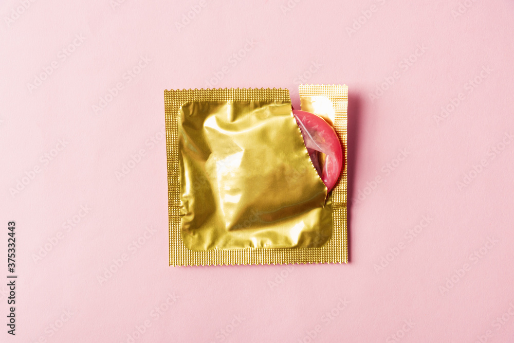 World sexual health or Aids day, Top view flat lay condom in wrapper pack is tear open, studio shot isolated on a pink background, Safe sex and reproductive health concept World sexual health or Aids day, Top view flat lay condom in wrapper pack is tear open, studio shot isolated on a pink background, Safe sex and reproductive health concept