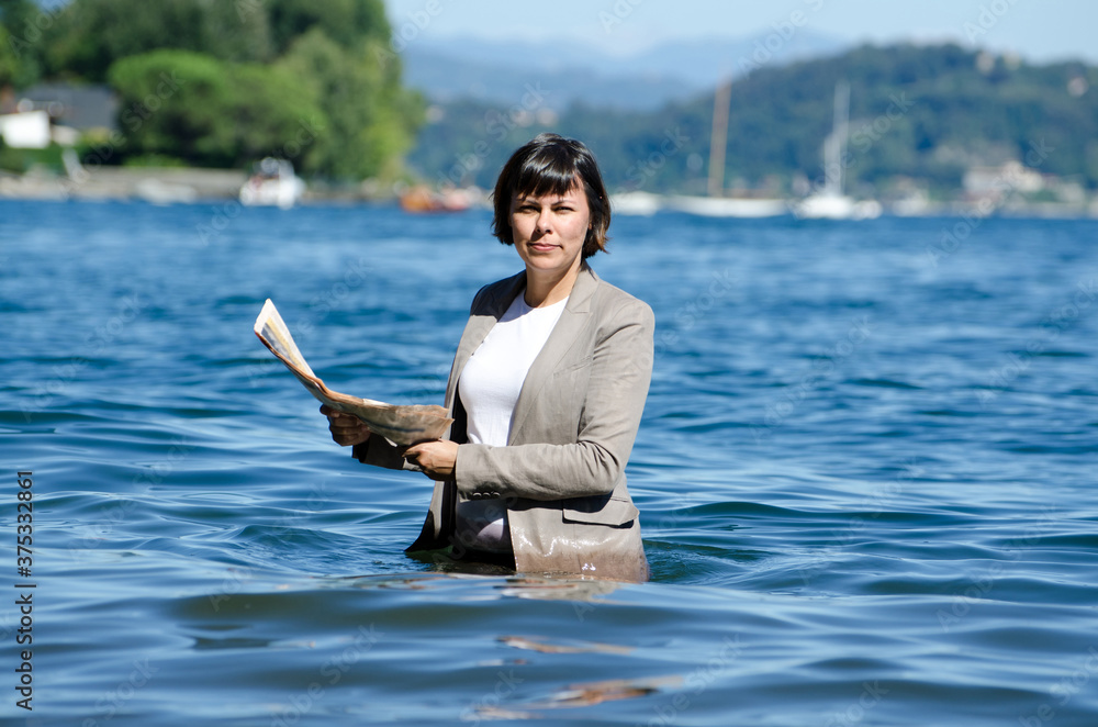 Fototapeta premium Elegant Business Woman with Suit Standing in the Water and Reading a Newspaper.