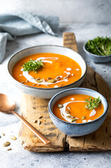 Vegetarian autumn pumpkin and carrot soup with cream, seeds and cilantro micro greens. Comfort food, fall and winter healthy slow food concept