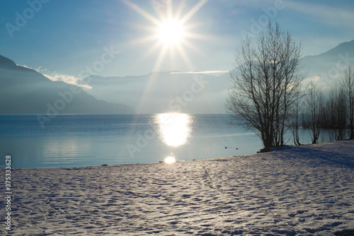 Alpine Lake Maggiore with Snow and Mountain with Sunbeam in Ascona, Switzerland. photo