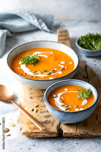 Vegetarian autumn pumpkin and carrot soup with cream, seeds and cilantro micro greens. Comfort food, fall and winter healthy slow food concept