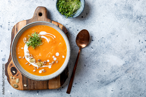 Vegetarian autumn pumpkin and carrot soup with cream, seeds and cilantro micro greens. Comfort food, fall and winter healthy slow food concept photo