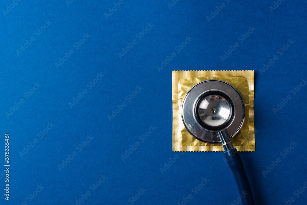 World sexual health or Aids day, Top view flat lay medical equipment, condom in pack and stethoscope, studio shot isolated on dark blue background, Safe sex and reproductive health concept World sexual health or Aids day, Top view flat lay medical equipment, condom in pack and stethoscope, studio shot isolated on dark blue background, Safe sex and reproductive health concept