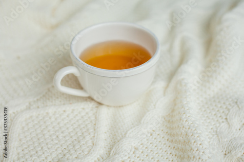 A mug of hot tea on a knitted blanket. Cozy autumn. Winter breakfast.