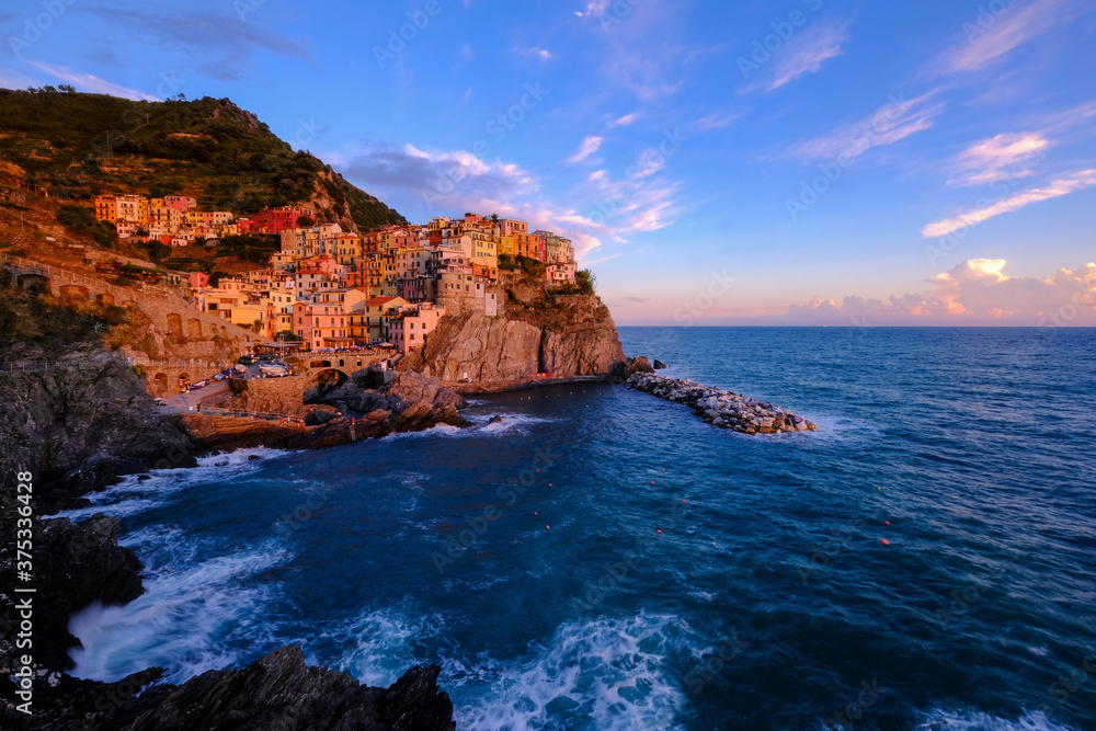 Colorful traditional houses on the rock over Mediterranean sea on dramatic sunset, Manarola, Cinque Terre, Italy