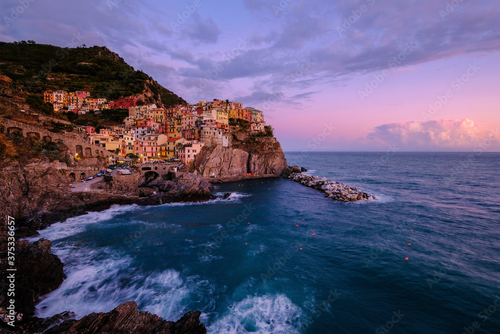 Colorful traditional houses on the rock over Mediterranean sea on dramatic sunset, Manarola, Cinque Terre, Italy