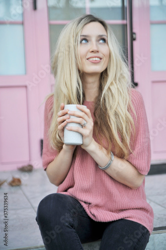 Beautiful woman with cup of hot drink outdoors. Autumn concept.