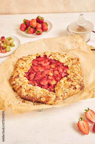 Delicious rhubarb strawberries gallate cake with ingredients on a white table photo