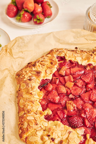 Delicious rhubarb strawberries gallate cake with ingredients on a white table photo