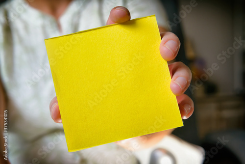 Woman showing a blank yellow note paper