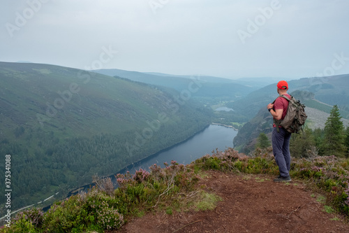 Tourist with backpack on the top of the mountain looking at the lake in Wicklow National Park 
