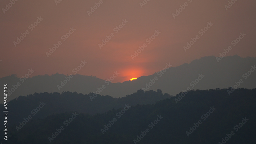 Sunset over a hill with hazy sky near Pha Tang town in Laos.