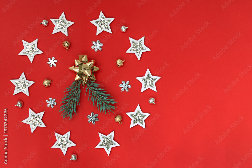Flat composition of Christmas decorations in white and gold and fir branches on a red background.