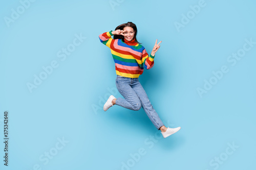 Full length body size view of her she nice-looking attractive lovely pretty funky cheerful cheery girl jumping having fun showing v-sign party time isolated blue pastel color background
