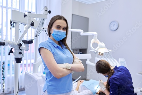Portrait of confident female dentist in medical mask with crossed arms